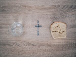 closeup photo of silver-colored cross pendant beside baked bread